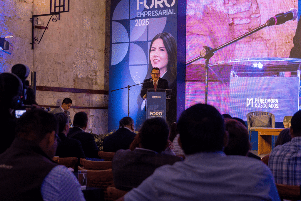 Conferencista hablando al micrófono en el evento de Pérez y Mora