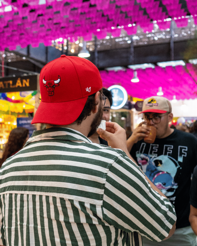 Hombre con gorra roja de espaldas probando el mezcal de Alma de Judas