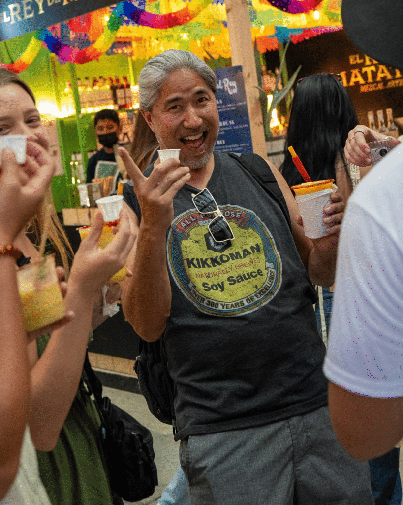 Hombre sonriendo a la cámara y mostrando su prueba de mezcal a la cámara en la feria del mezcal 2025