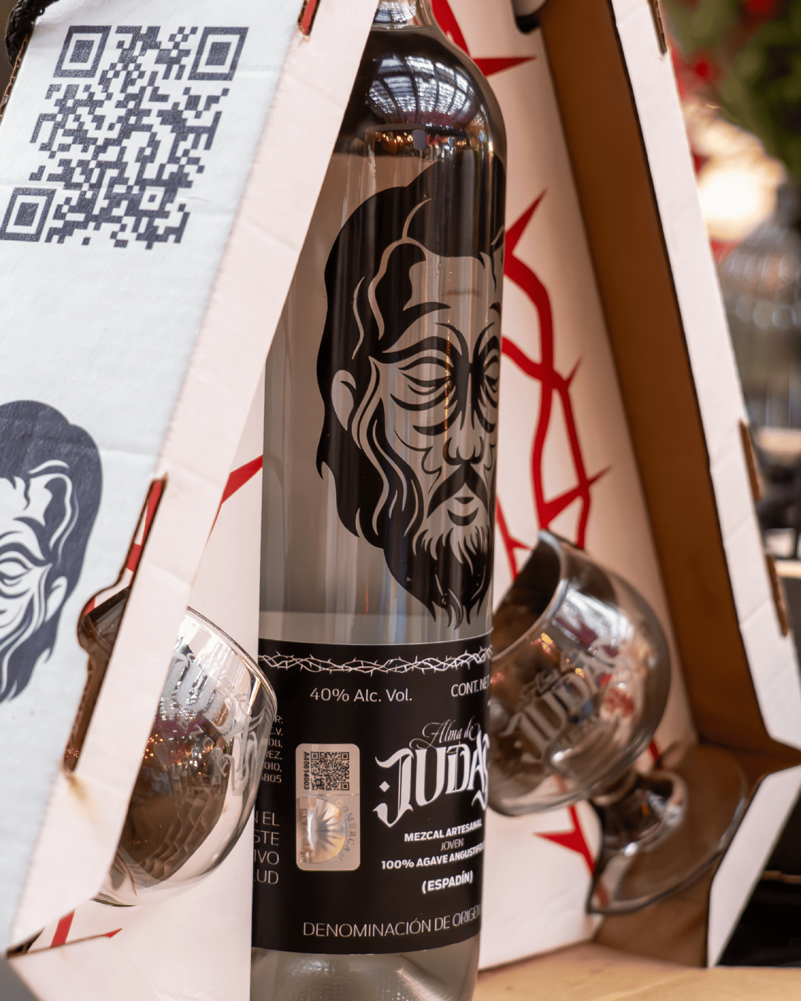 Close up de la botella de Alma de Judas, en un empaque triangular blanco con rojo