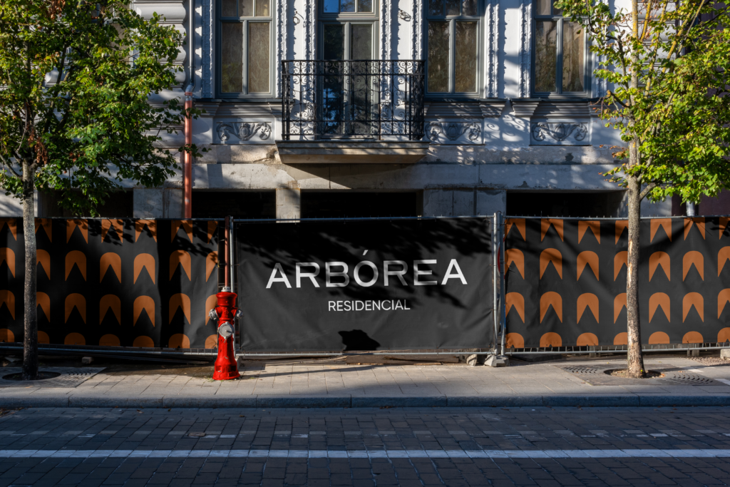 Mock up de una calle con el logo de arbórea residencial en una lona negra, junto con el patrón de la marca