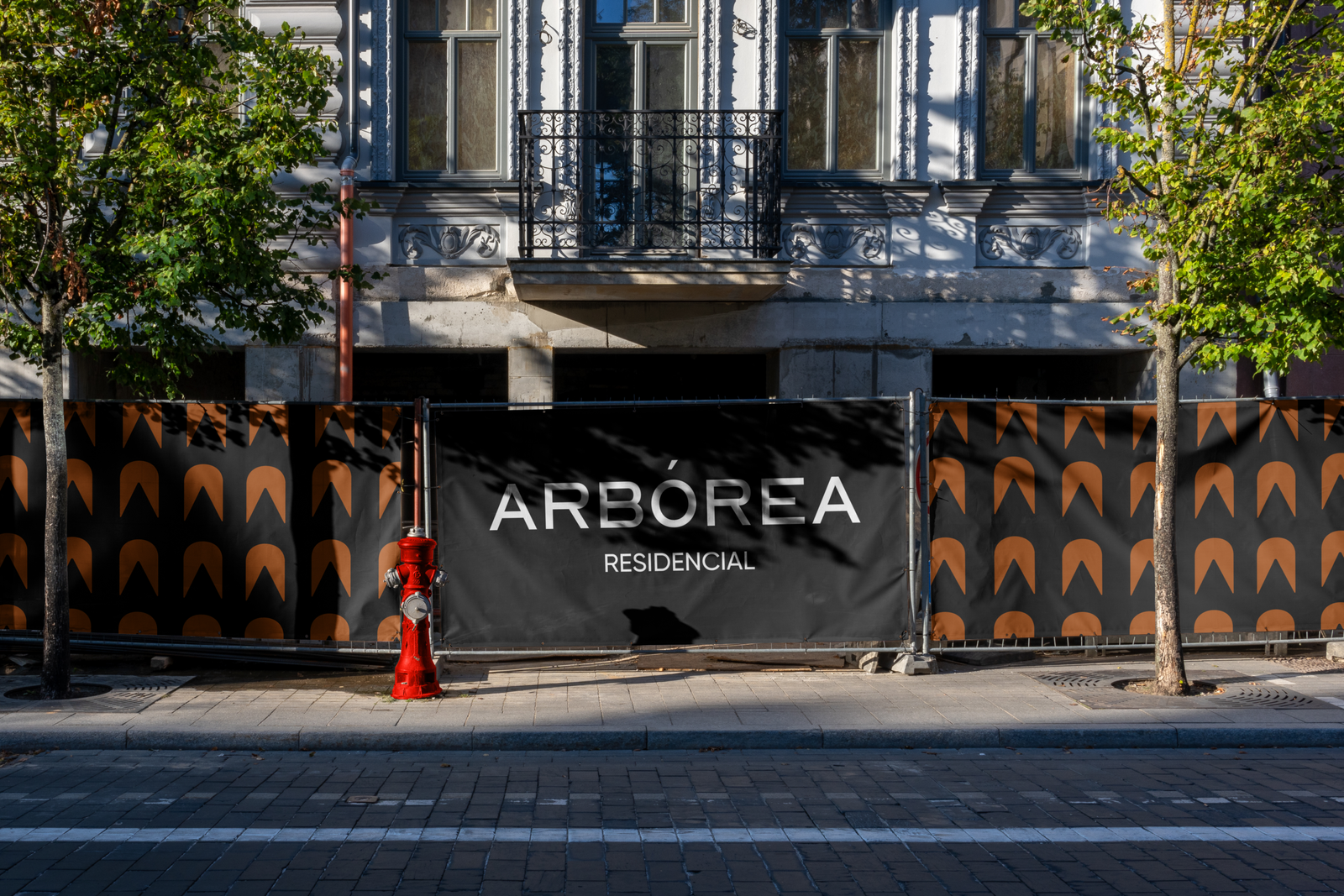 Mock up de una calle con el logo de arbórea residencial en una lona negra, junto con el patrón de la marca