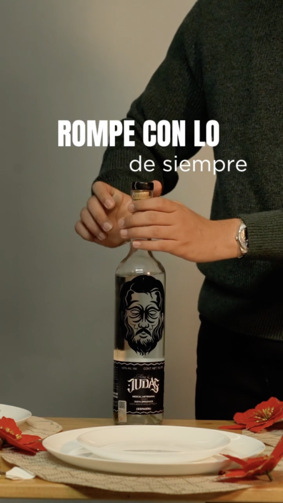 Hombre sirviendo copas para brindar con la botella de Alma de Judas