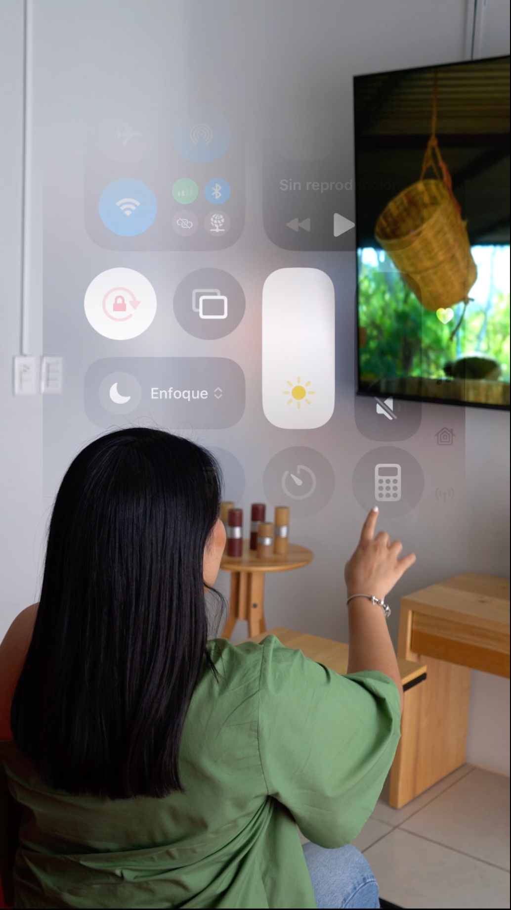 Chica simulando usar un teléfono celular en un ambiente de sala con una tv de fondo